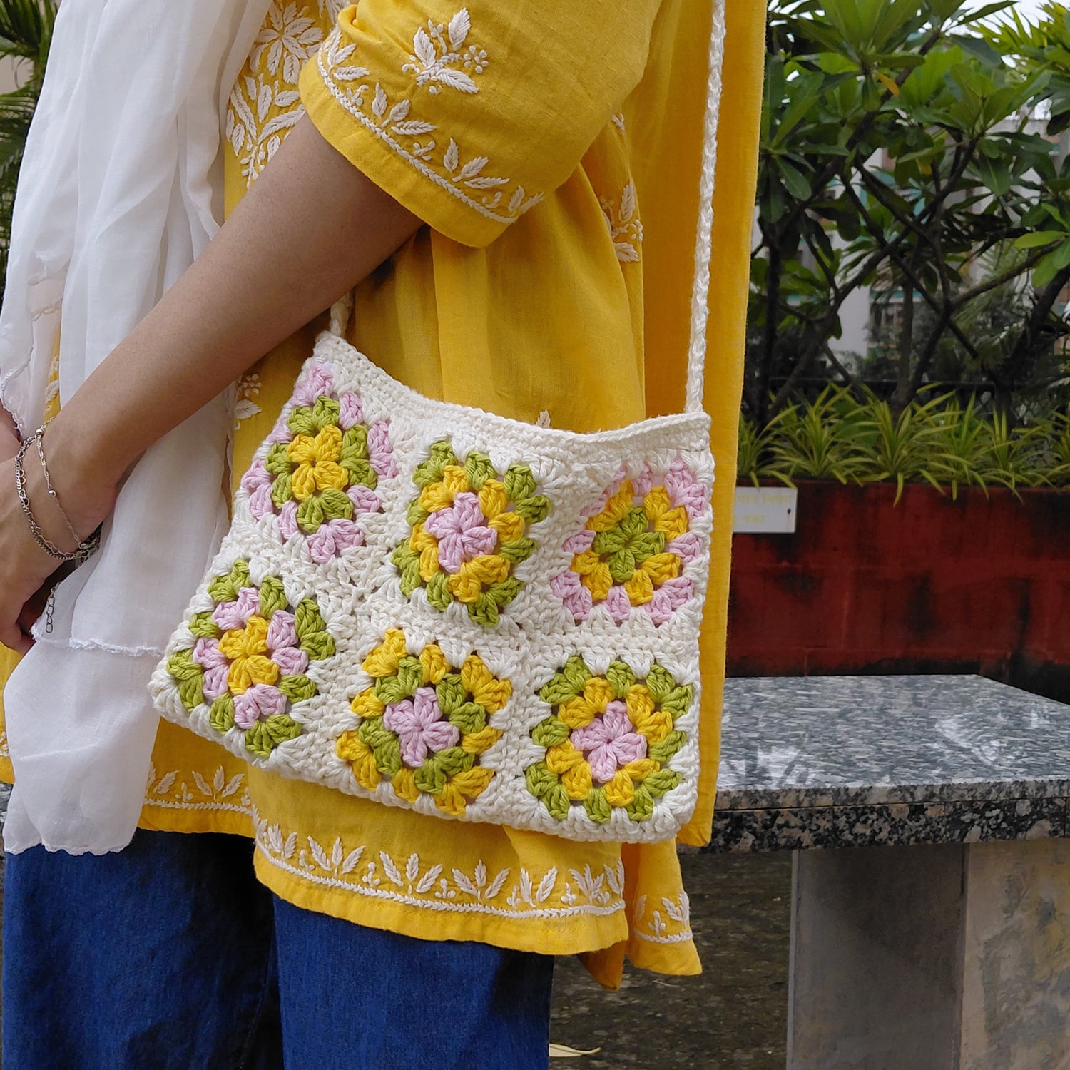 Handcrafted crochet shoulder bag with blue and yellow squares, stylish sustainable fashion accessory for women.