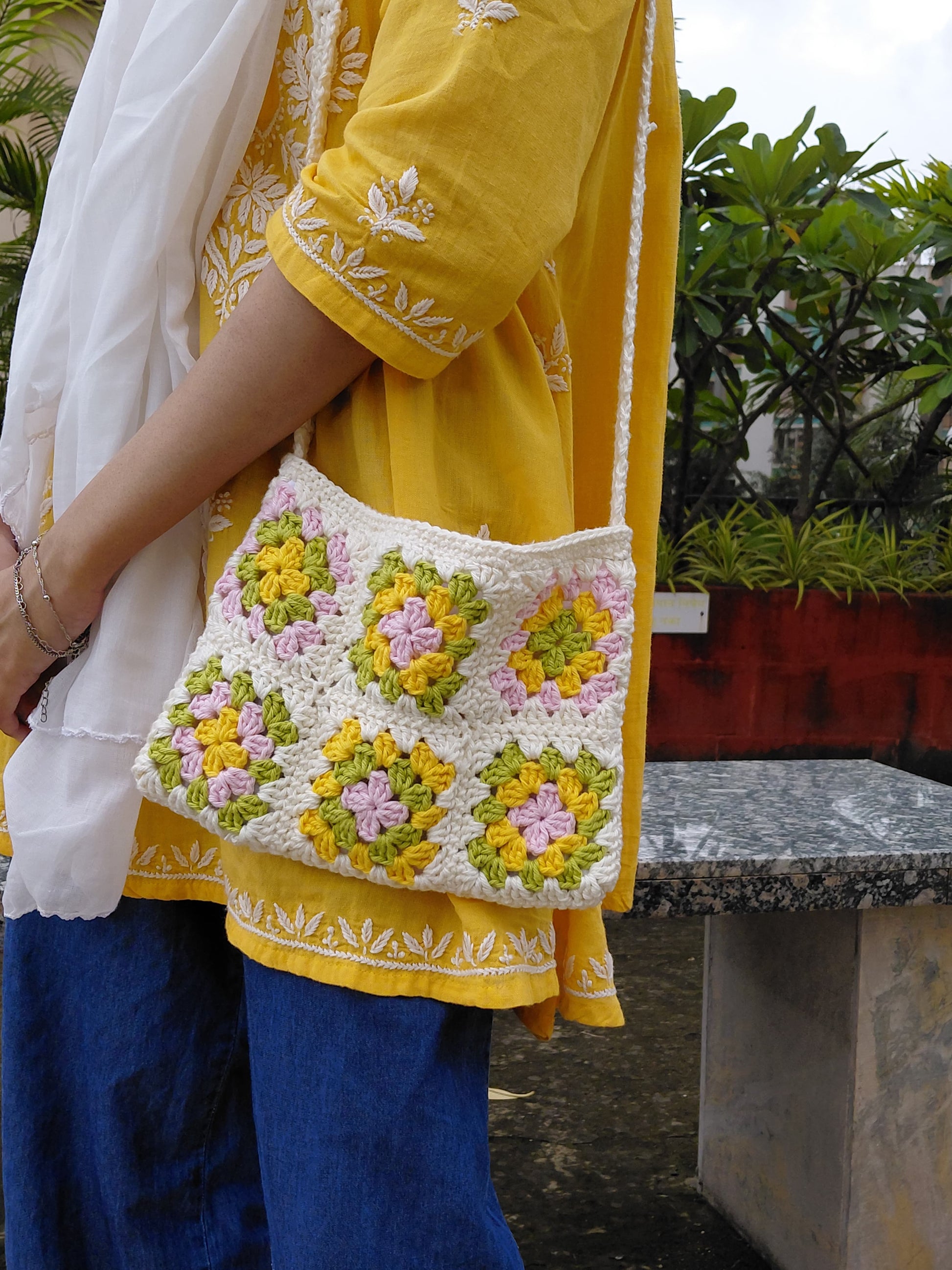 Handcrafted crochet shoulder bag with blue , pink , white and yellow squares, stylish sustainable fashion accessory for women.
